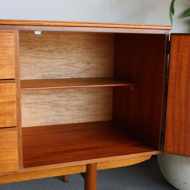 Vintage teak mid-century British Austinsuite sideboard open storage, visible wood grain and slender legs.