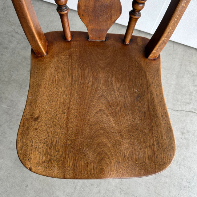 Vintage teak mid-century British kitchen chair seat with smooth wood grain and turned spindle backrest legs.