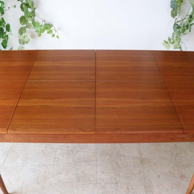 Mid-century vintage teak dining table with rich wood grain, clean lines, and sturdy tapered legs.