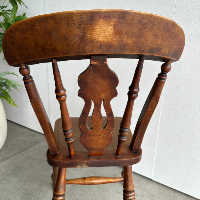 Vintage British teak kitchen chair with turned spindles, decorative center splat, and mid-century design showing rich wood.