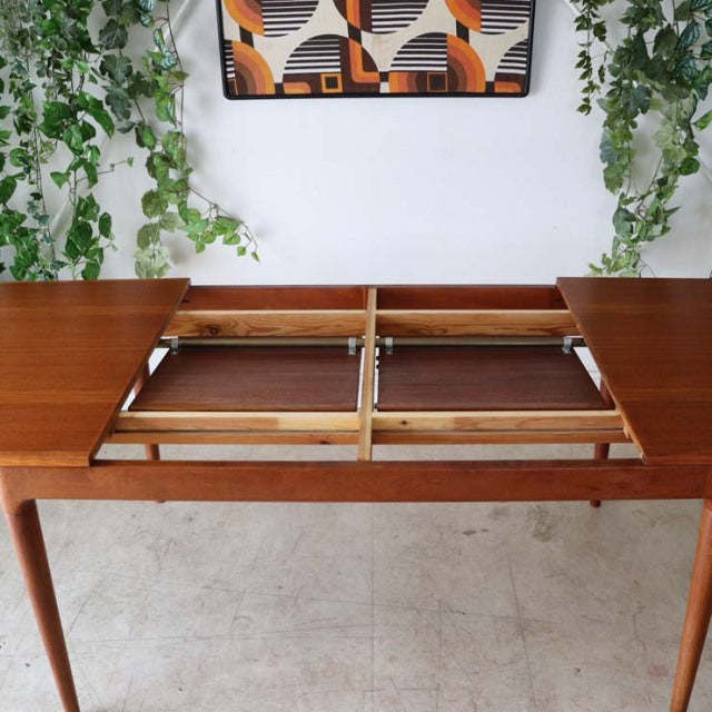 Mid-century vintage teak dining table from Denmark with rich wood grain, clean lines, and tapered legs, extending mechanism.