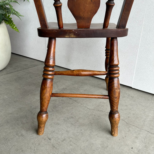 Vintage British mid-century teak kitchen chair with turned legs and sculpted backrest, rich wood grain finish.