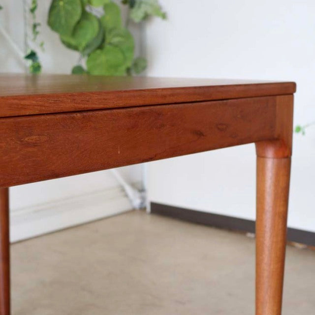 Mid-century Danish teak dining table corner with rounded legs and visible wood grain in vintage British style.