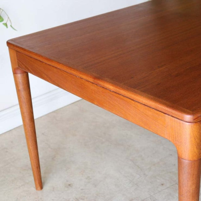 Vintage Danish mid-century teak dining table with smooth wood grain and tapered round legs.