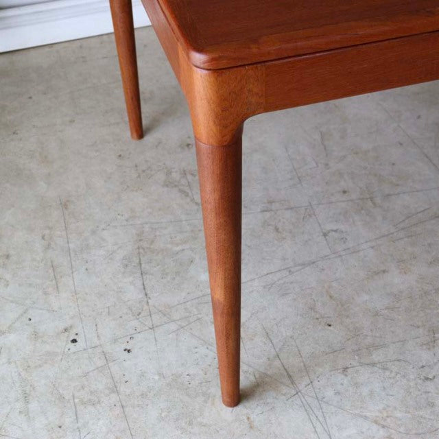 Mid-century vintage Danish teak dining table corner with rounded edges and tapered legs showing rich wood grain.