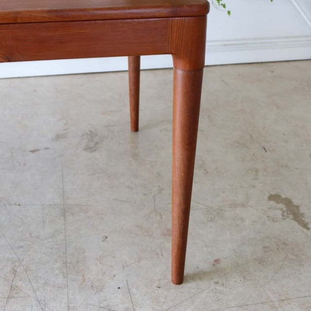 Vintage mid-century teak dining table leg from British-Denmark design, sleek tapered form, rich wood grain visible.