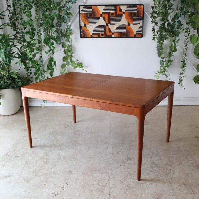 Mid-century vintage teak dining table from Denmark with clean rectangular top and tapered legs, rich wood grain visible.