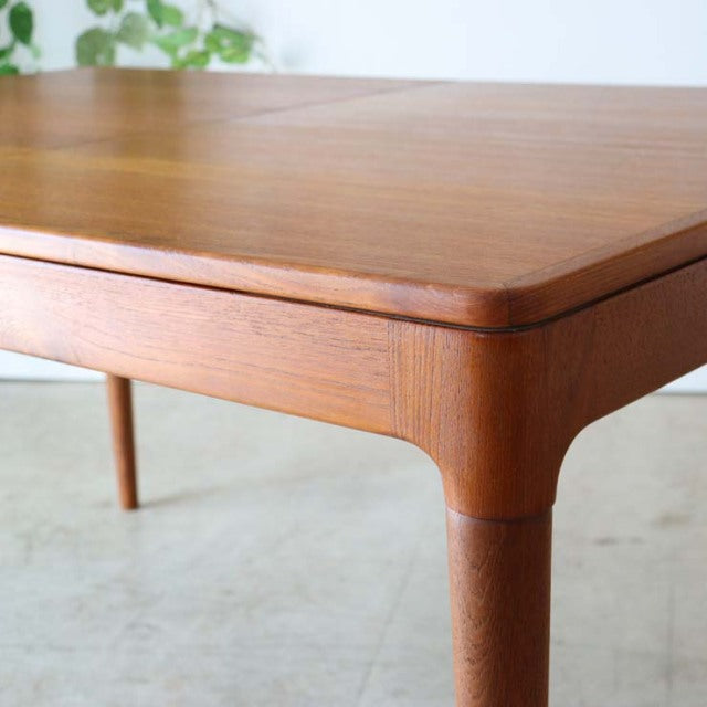 Vintage mid-century teak dining table from Denmark with rounded edges and tapered legs showcasing rich wood grain.