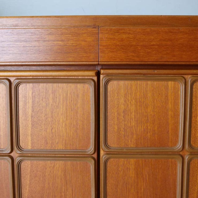 Mid-century British vintage teak sideboard with textured wood grain and recessed rectangular panel doors.