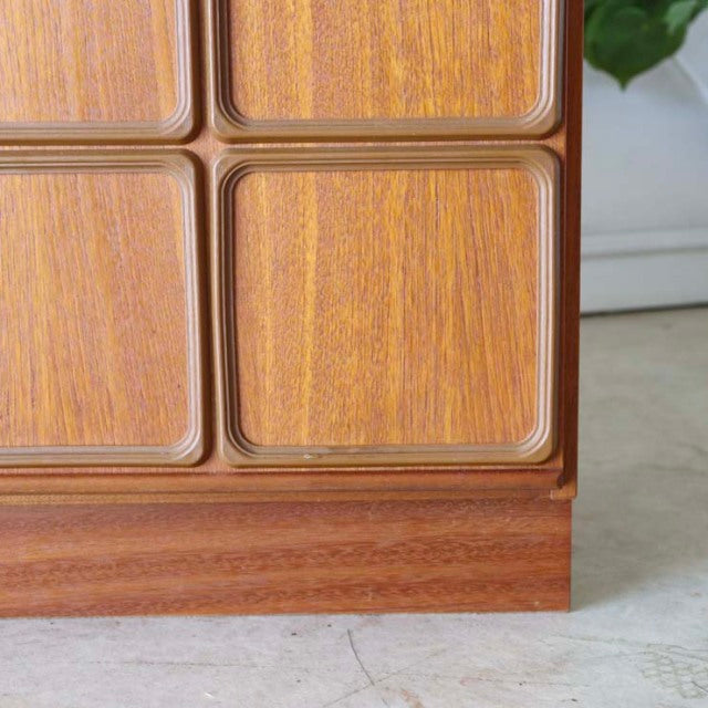 Vintage mid-century McIntosh teak sideboard corner showing smooth wood grain, rounded rectangular panel detailing, and.