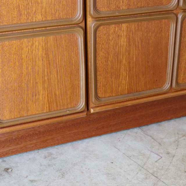 Close-up of vintage mid-century British teak sideboard with detailed wood grain and rounded panel edges.