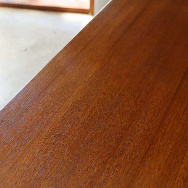 Close-up of vintage teak wood grain on mid-century McIntosh sideboard with smooth, warm-toned surface.
