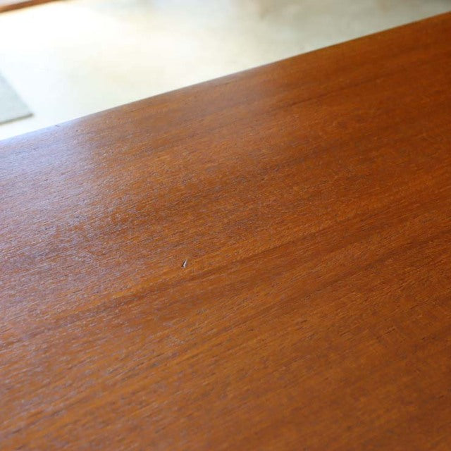 Close-up of vintage mid-century teak wood grain with smooth finish on British McIntosh sideboard surface.