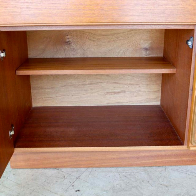 Mid-century British vintage teak sideboard interior with wood grain paneling and adjustable shelf.