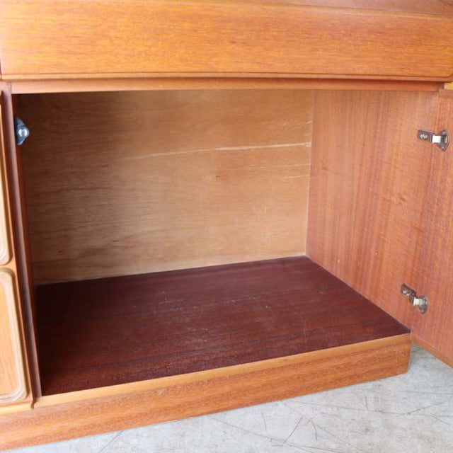 Mid-century British teak sideboard cabinet interior with visible wood grain and sturdy hinges.