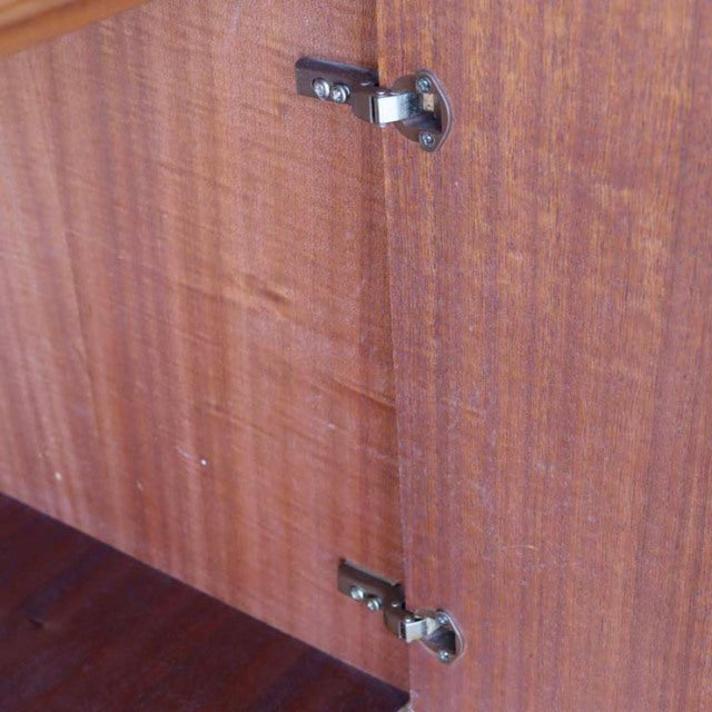 Close-up of vintage teak wood grain and metal hinges on British mid-century McIntosh sideboard interior from Denmark.