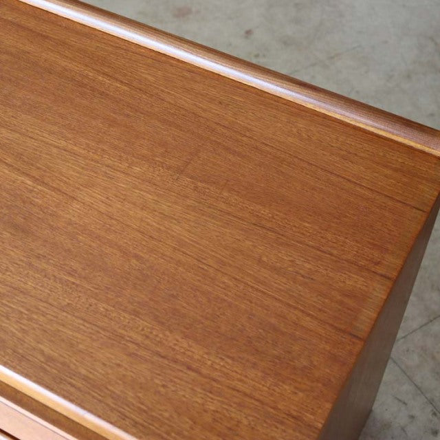 Mid-century British McIntosh teak sideboard showing smooth wood grain and rounded edges in vintage Danish design style.
