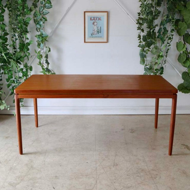 Mid-century vintage teak dining table by Johannes Andersen with rectangular top and tapered legs, showcasing warm wood grain .