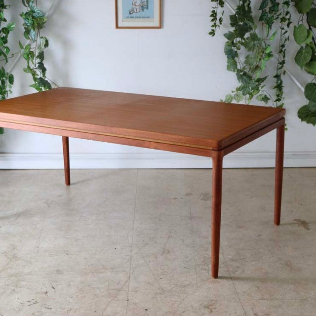 Mid-century vintage teak dining table with slender tapered legs and smooth rectangular top, British and Danish design.