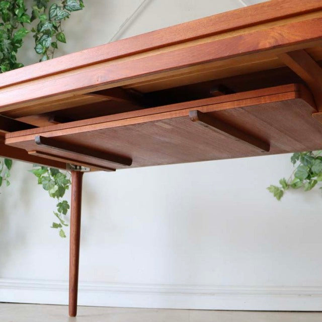 Mid-century vintage teak dining table with tapered legs and smooth grain, Danish British design.