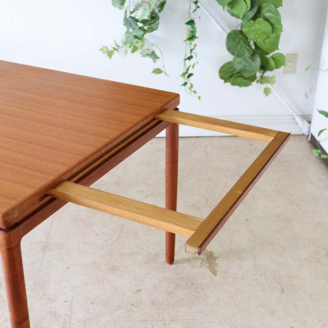 Mid-century vintage teak dining table by Johannes Andersen with extending mechanism, smooth wood grain, and slender round.