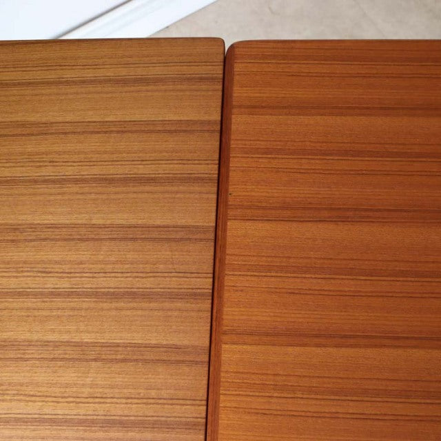 Close-up of vintage mid-century Danish teak dining table showing rich wood grain and warm tone, highlighting smooth.