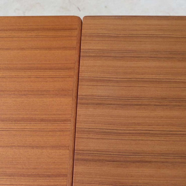 Vintage teak dining table top showing fine wood grain and smooth rectangular mid-century surface with subtle rounded edges,.
