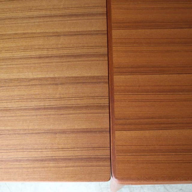 Close-up of vintage teak dining table top showing rich wood grain and smooth finish, mid-century British-Denmark design.