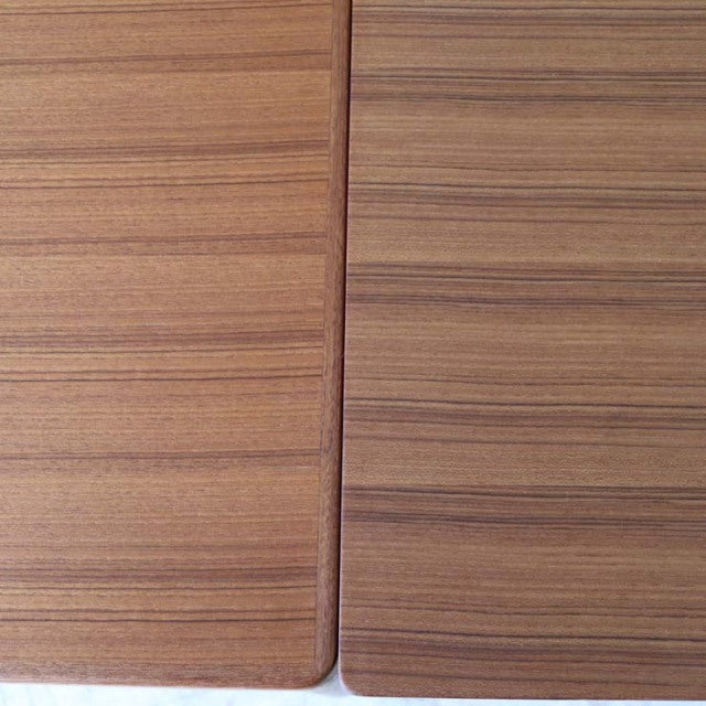 Close-up of vintage mid-century teak dining table top with smooth wood grain and rounded edges, British Denmark design.