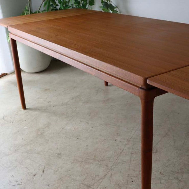 Mid-century vintage teak dining table from Denmark with sleek tapered legs and smooth wood grain surface.