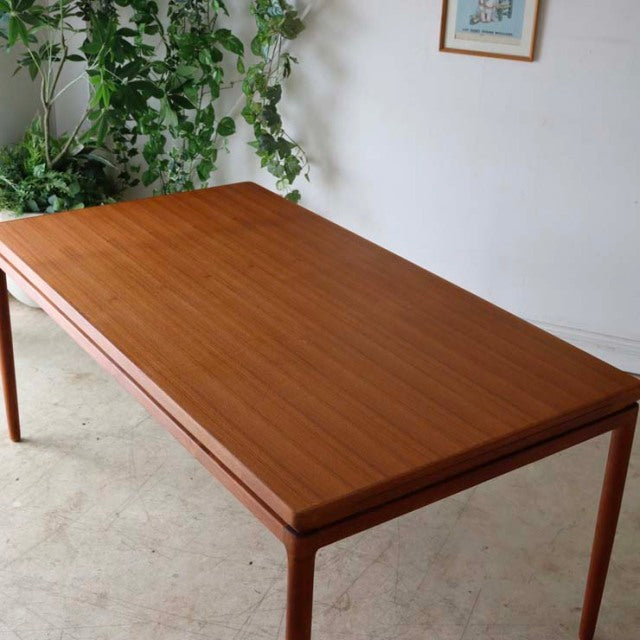 Mid-century vintage teak dining table by Johannes Andersen with sleek rectangular top, slender tapered legs, and smooth wood .