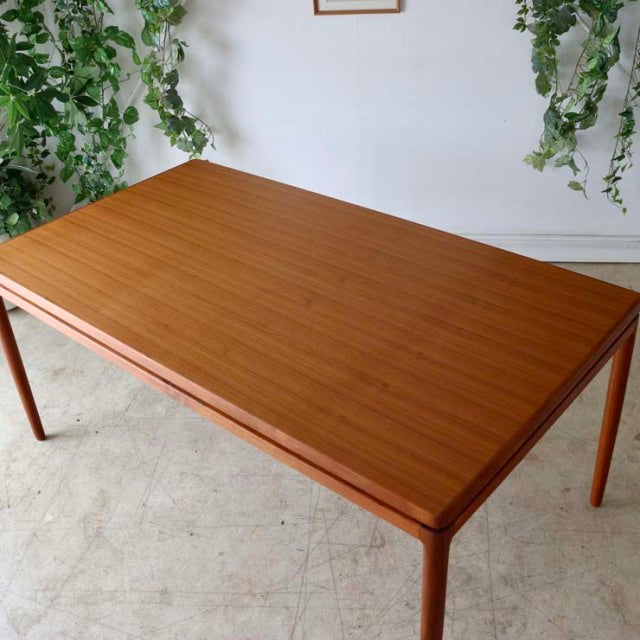 Mid-century vintage teak dining table by Johannes Andersen, rectangular with smooth wood grain and slender tapered legs,.