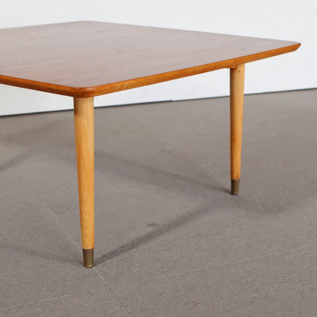 Mid-century vintage teak coffee table with sleek tapered legs and brass-capped feet, Scandinavian design influence.