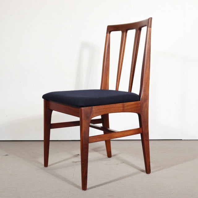 Vintage mid-century teak dining chair with a sleek British design, slender vertical slats, and dark upholstered seat,.