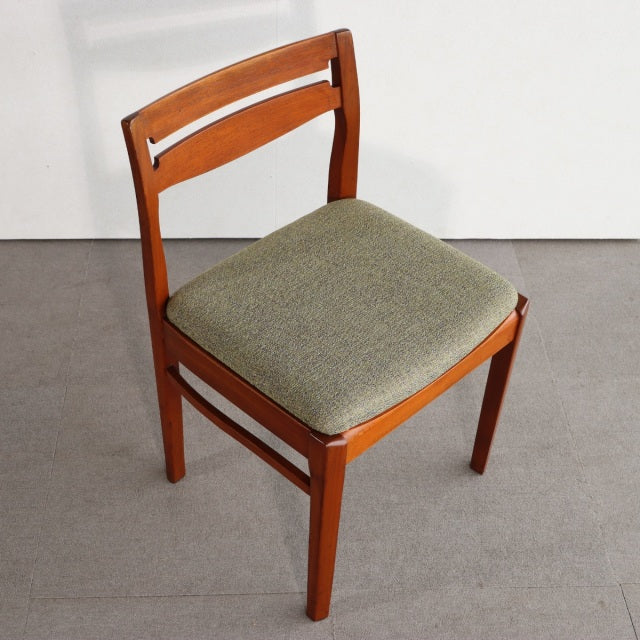 Mid-century vintage British teak dining chair with green upholstered seat and slatted backrest.