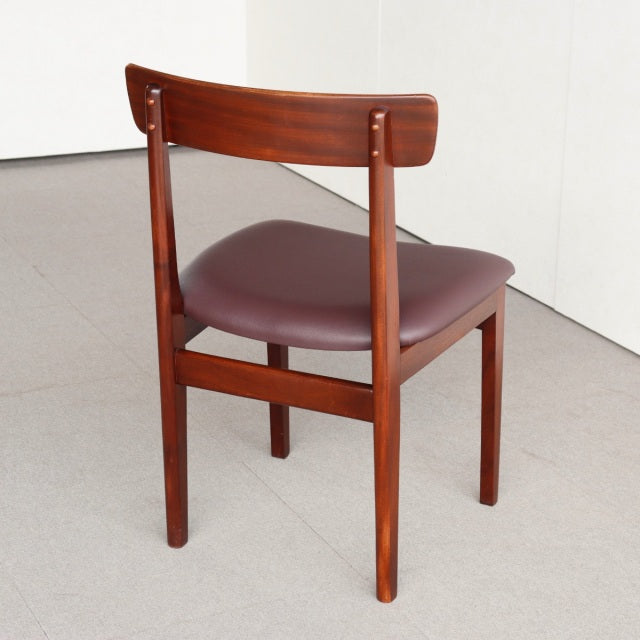 Mid-century British vintage teak dining chair with smooth curved backrest and burgundy cushioned seat.