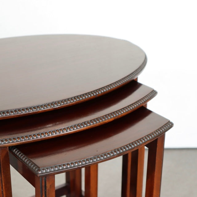Set of three British vintage teak nest tables with mid-century round tops and detailed beaded edges, slender square legs,.