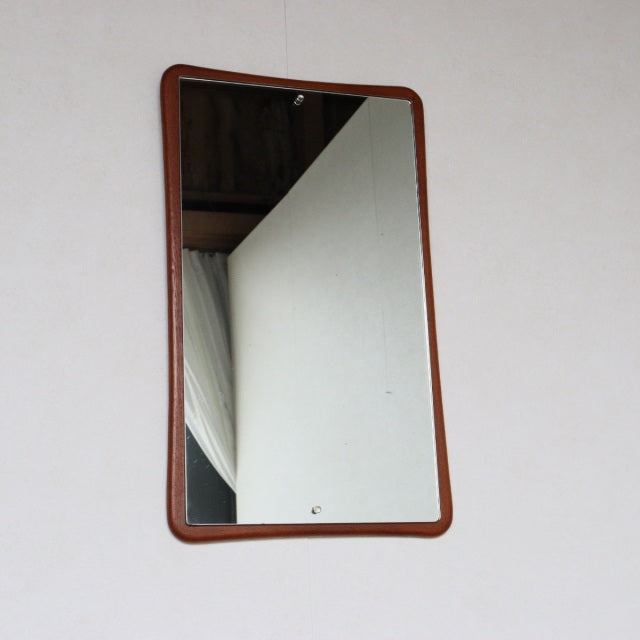 Mid-century British vintage wall mirror with gently curved teak frame and smooth wood grain finish.