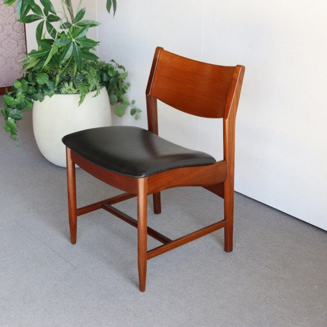 Mid-century British vintage dining chair with teak frame, black leather seat, and tapered legs.