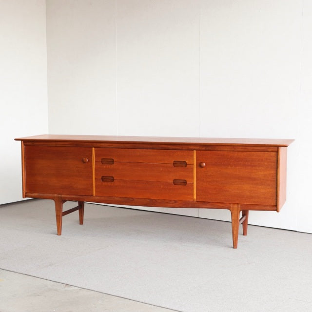 Mid-century British vintage teak sideboard by YOUNGER with rich wood grain, three center drawers, and tapered legs.