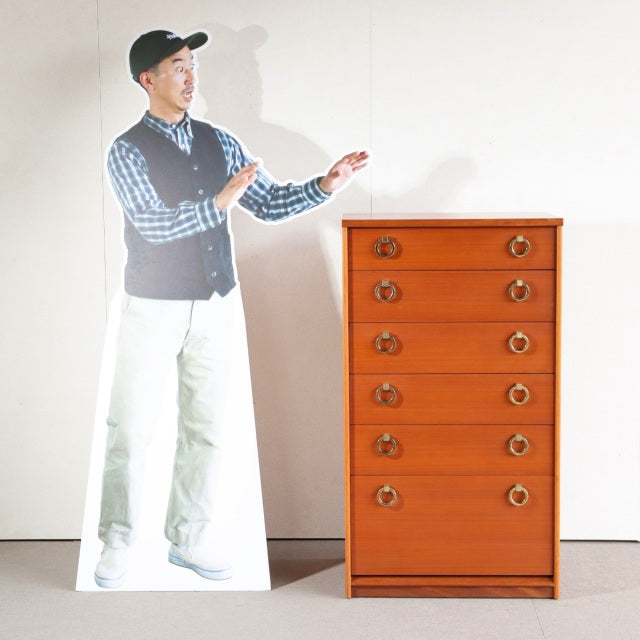 Mid-century British vintage teak chest with six drawers, round brass handles, and clean wood grain, standing on short.