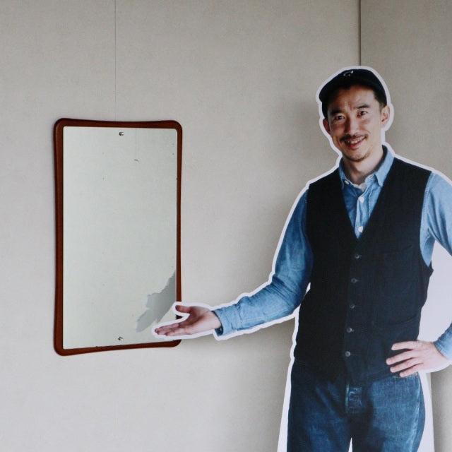 Vintage British mid-century teak wall mirror with gently curved edges and warm wood grain finish.