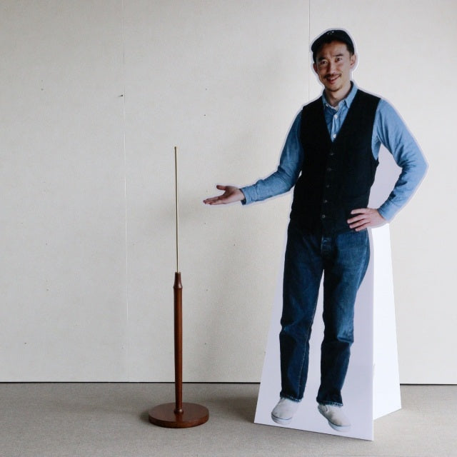 Slim mid-century British vintage teak floor lamp with round base and slender brass rod.