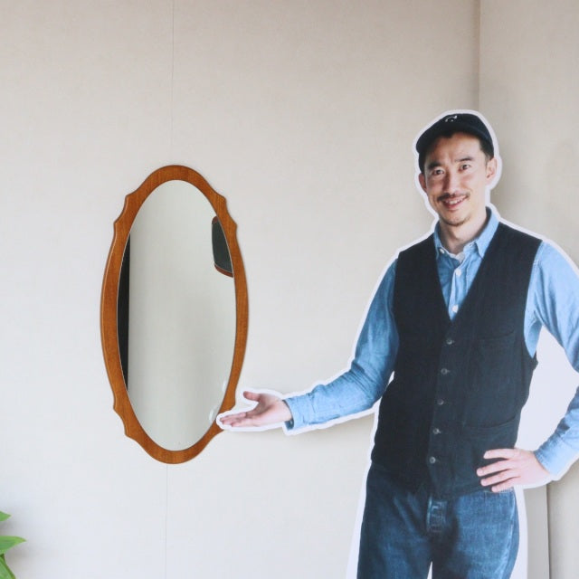 Vintage mid-century British teak wall mirror with elegant oval shape and smooth wood grain finish.