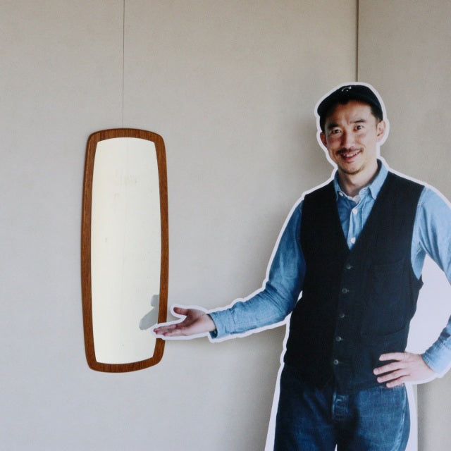 Mid-century vintage teak wall mirror from British-Danish design, slender vertical frame with smooth wood grain and rounded.