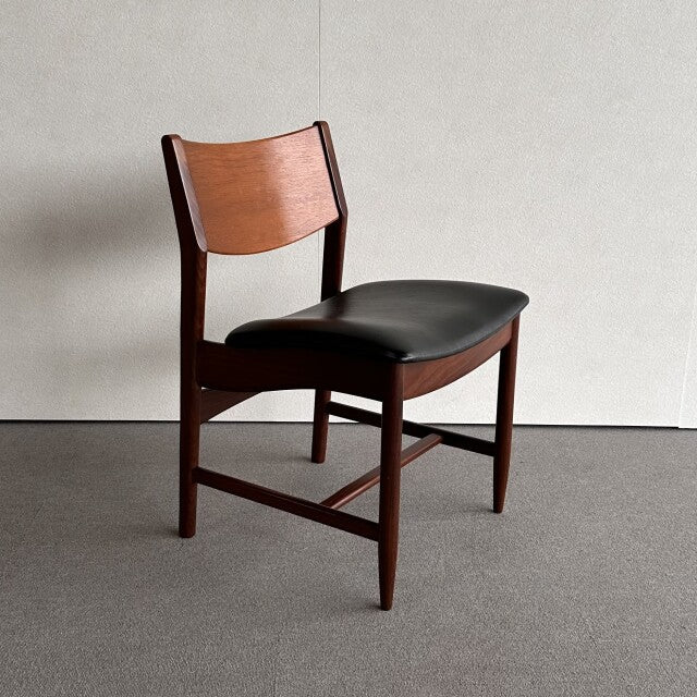 Mid-century British vintage dining chair with teak wood frame, visible wood grain, and black leather seat cushion.