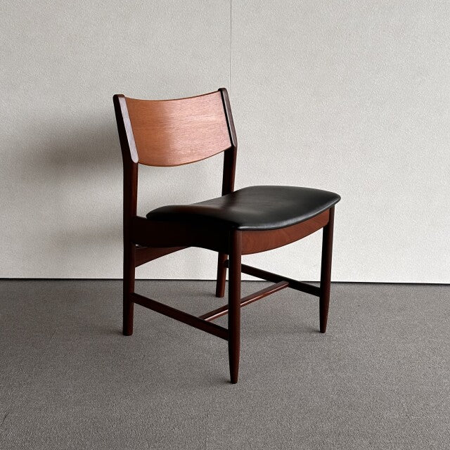 Mid-century British vintage dining chair with teak wood frame, black leather seat, and exposed wood grain.