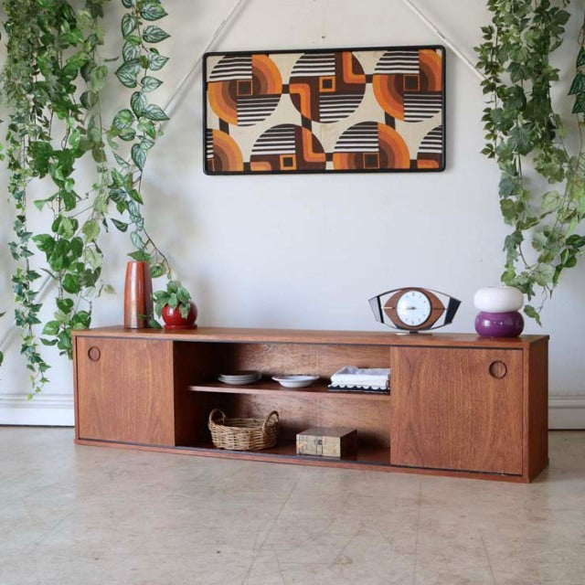 British mid-century teak lowboard by AVALON with rich wood grain, sliding doors, and tapered legs.