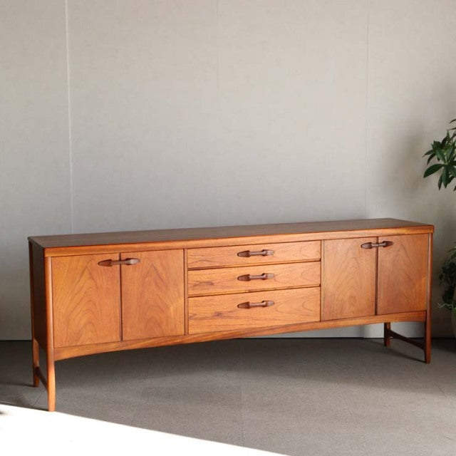Vintage teak sideboard by British brand Nathan, mid-century design with smooth wood grain, four tapered legs, two cabinets,.