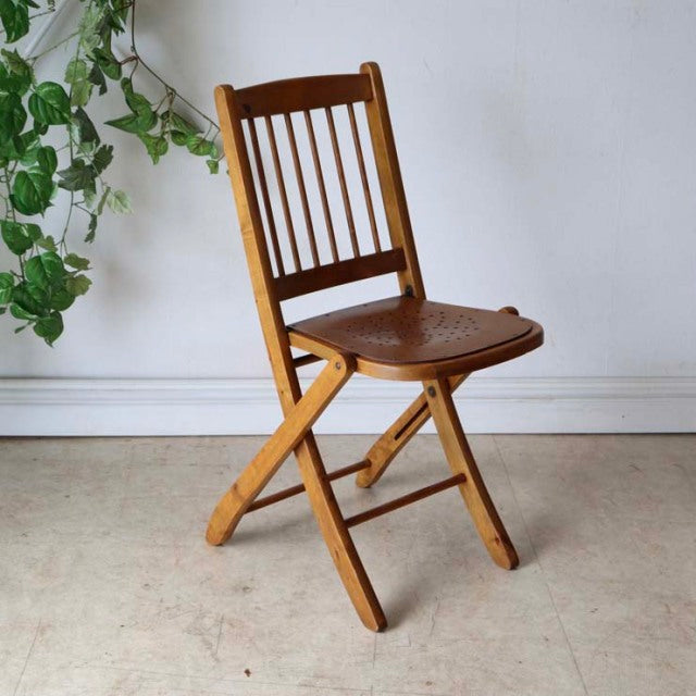 Vintage British mid-century teak folding chair with vertical slat back and contoured seat showing natural wood grain.